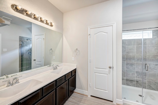 bathroom with hardwood / wood-style floors, vanity, and a shower with door