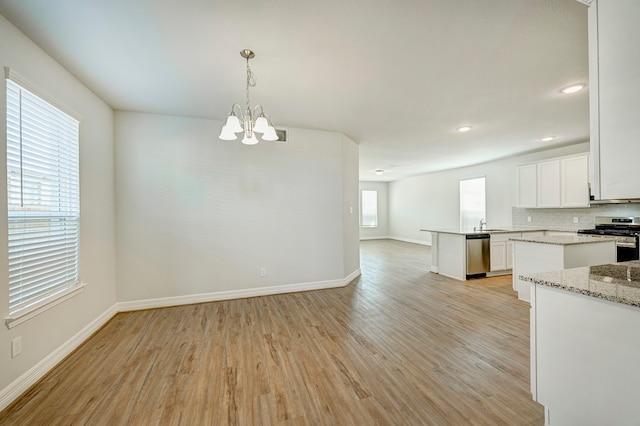 interior space featuring white cabinets, stainless steel appliances, hanging light fixtures, and a healthy amount of sunlight