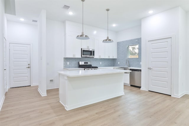 9339 Lavender St, North Houston, TX 77016 - kitchen featuring appliances with stainless steel finishes, light wood-type flooring, light countertops, white cabinetry, and tasteful backsplash
