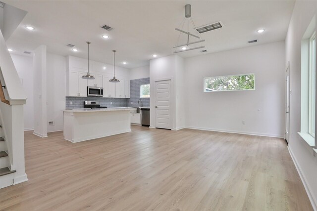 9339 Lavender St, North Houston, TX 77016 - kitchen featuring stainless steel appliances, light countertops, white cabinetry, open floor plan, and healthy amount of natural light