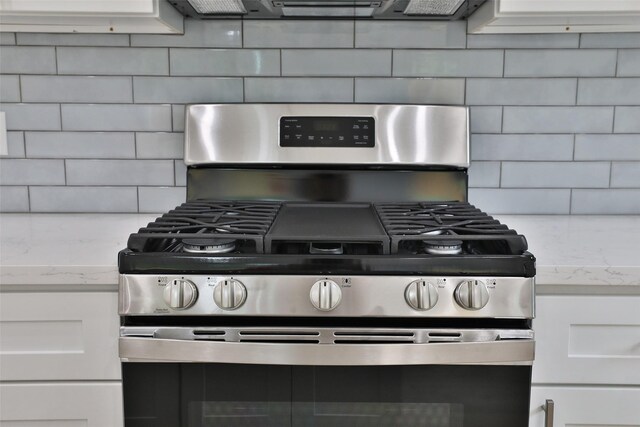 9339 Lavender St, North Houston, TX 77016 - kitchen view of gas stove, backsplash, white cabinetry, and light stone counters