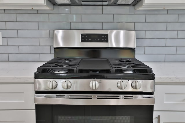 9339 Lavender St, North Houston, TX 77016 - kitchen view of stainless steel gas range, tasteful backsplash, white cabinets, and light stone countertops