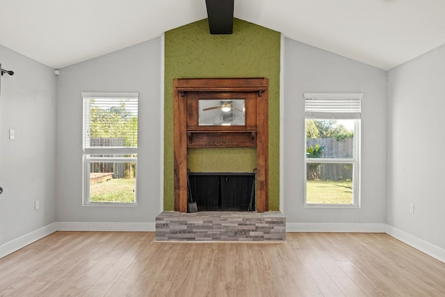 unfurnished living room with lofted ceiling with beams, a fireplace, and light hardwood / wood-style floors