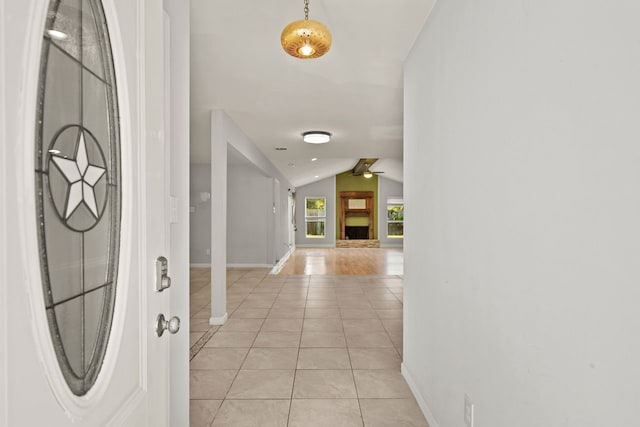 foyer entrance with ceiling fan, light tile patterned flooring, and vaulted ceiling