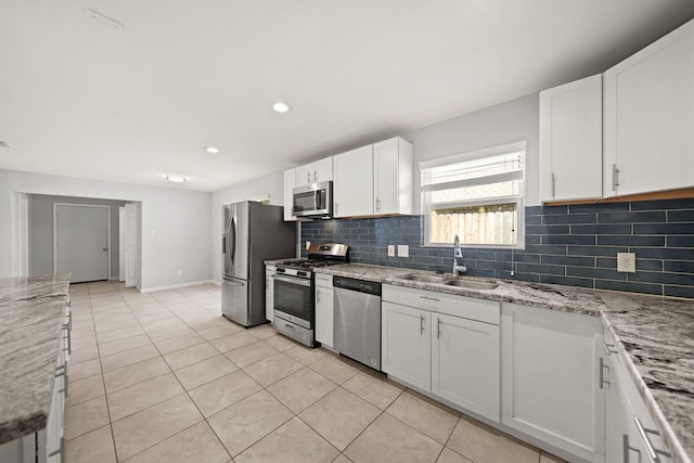 kitchen featuring white cabinets, appliances with stainless steel finishes, light stone counters, and sink