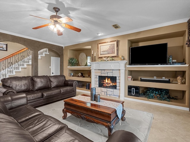 living room with a stone fireplace, built in features, and ornamental molding