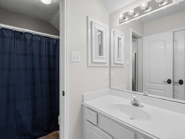 bathroom featuring a shower with shower curtain, vanity, lofted ceiling, and a textured ceiling