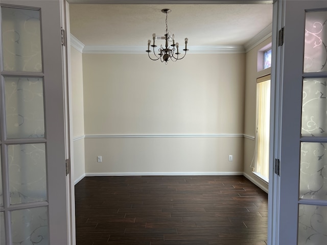 spare room featuring dark hardwood / wood-style flooring, ornamental molding, and an inviting chandelier