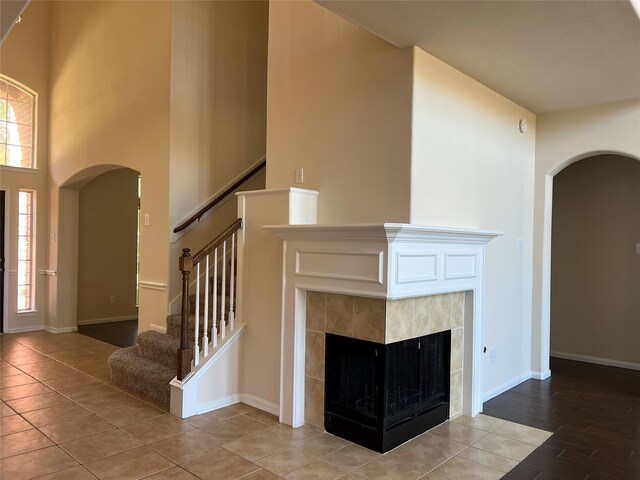 unfurnished living room featuring hardwood / wood-style flooring, a healthy amount of sunlight, a fireplace, and a high ceiling