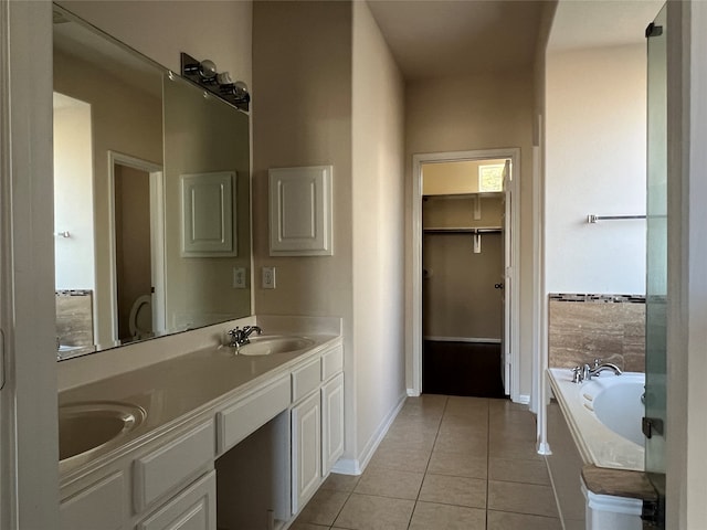 bathroom with tile patterned flooring, vanity, and tiled tub