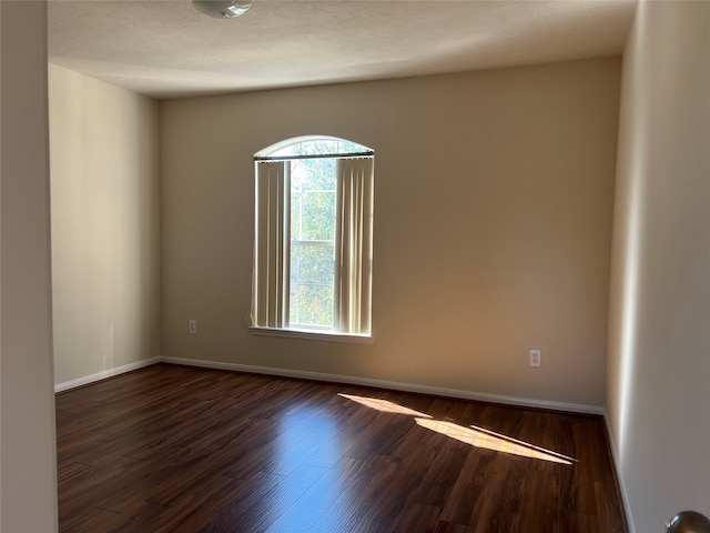 unfurnished room featuring a textured ceiling and dark hardwood / wood-style floors