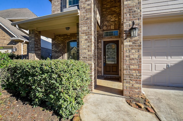 entrance to property featuring a garage and brick siding