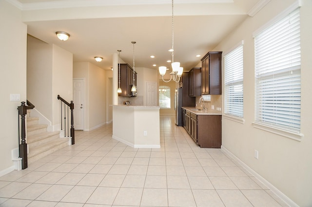 kitchen featuring an inviting chandelier, sink, hanging light fixtures, light tile patterned floors, and dark brown cabinetry