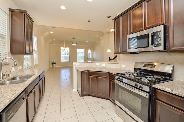 kitchen featuring kitchen peninsula, appliances with stainless steel finishes, ceiling fan with notable chandelier, sink, and pendant lighting