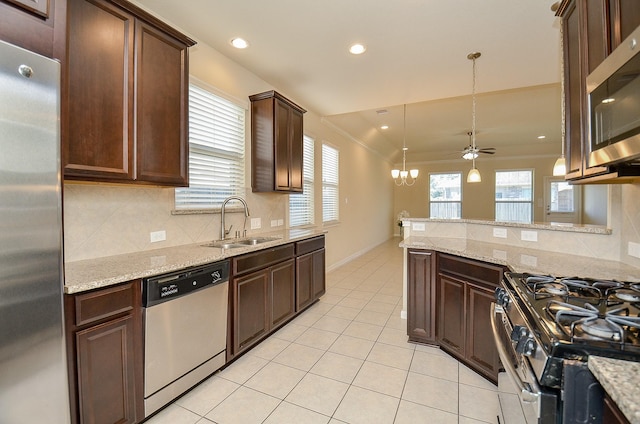 kitchen with ceiling fan with notable chandelier, sink, light stone countertops, appliances with stainless steel finishes, and decorative light fixtures