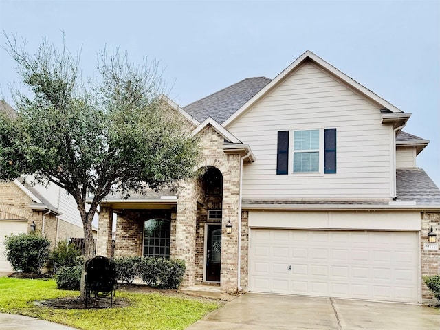 traditional-style home with an attached garage, roof with shingles, concrete driveway, and brick siding