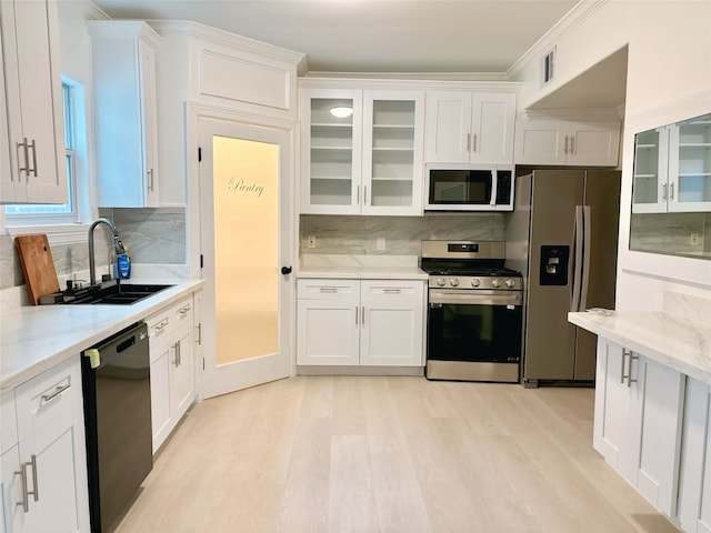 kitchen with appliances with stainless steel finishes, tasteful backsplash, light stone counters, sink, and white cabinetry