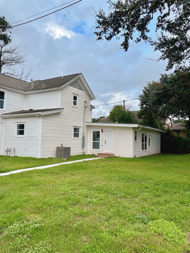 back of house featuring a yard and central AC