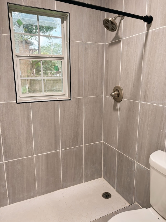 bathroom with a tile shower and toilet