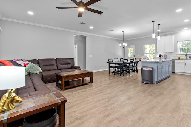 living room with ceiling fan with notable chandelier, light wood-type flooring, and crown molding