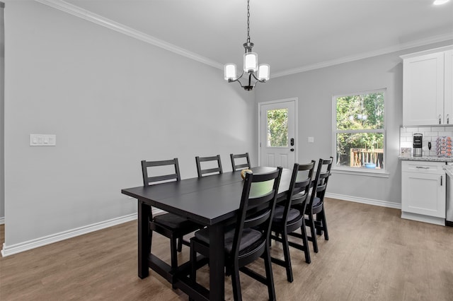 dining space featuring light wood-type flooring, ornamental molding, and a notable chandelier