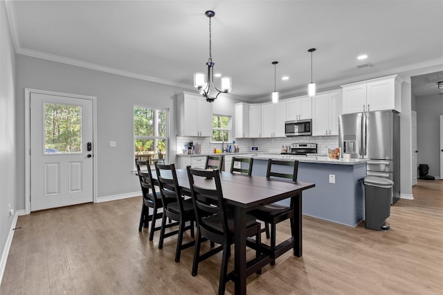 dining room featuring light hardwood / wood-style floors, ornamental molding, and an inviting chandelier