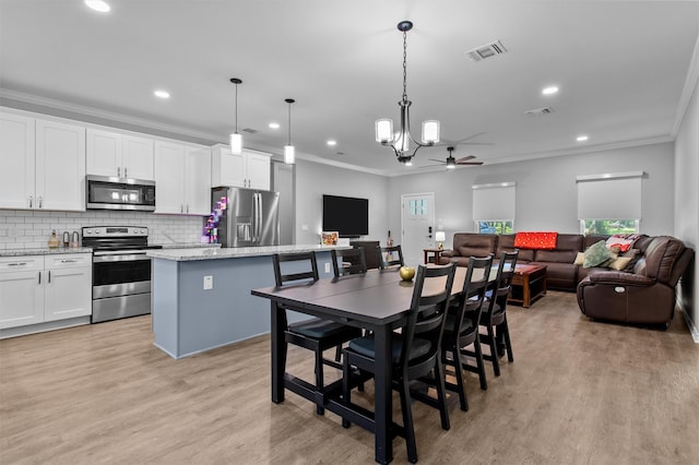 kitchen featuring stainless steel appliances, a kitchen island, ceiling fan, decorative light fixtures, and white cabinetry