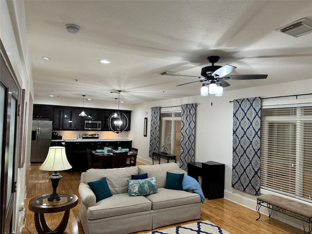 living room with ceiling fan, a textured ceiling, and hardwood / wood-style flooring