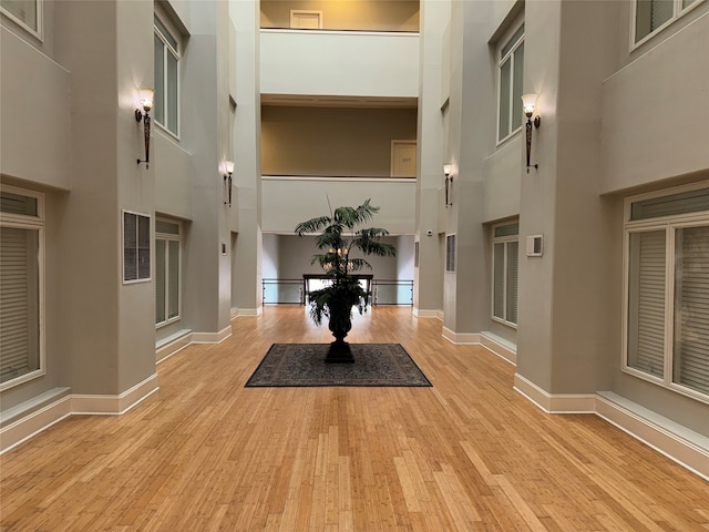 entrance foyer with light wood-type flooring and a towering ceiling