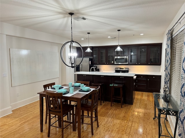 dining space with light hardwood / wood-style flooring and a notable chandelier