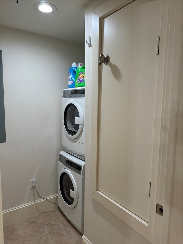 washroom featuring stacked washer and dryer and light tile patterned flooring