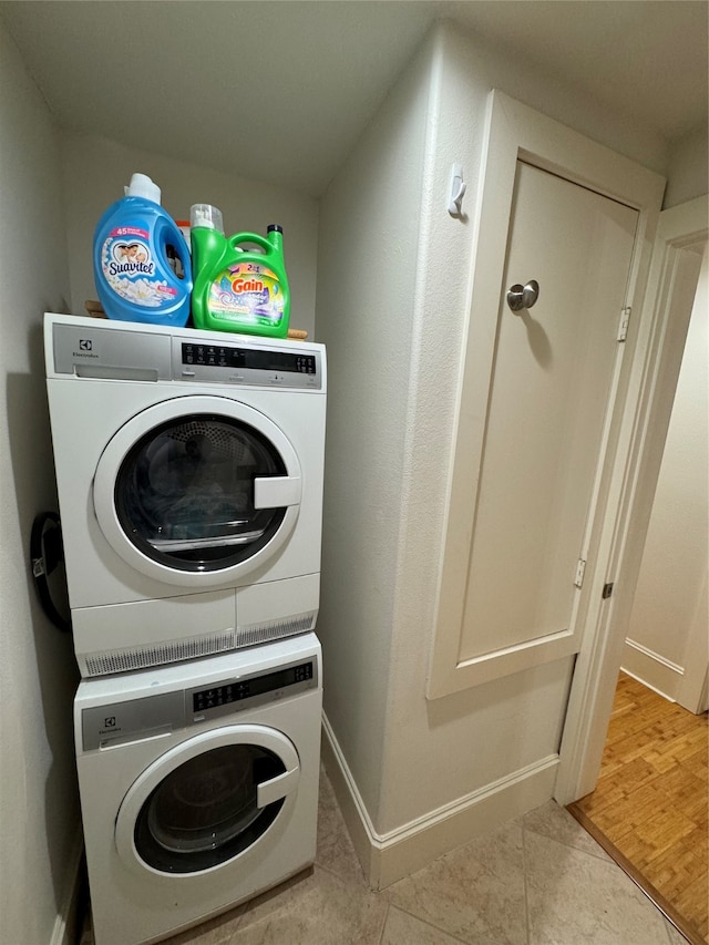 laundry area with stacked washing maching and dryer and light wood-type flooring