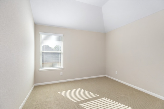 carpeted empty room featuring lofted ceiling