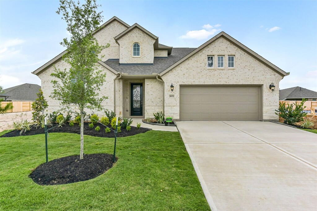 16171 Sheridan River Trl, Conroe, TX 77302 - french country inspired facade featuring concrete driveway, a front lawn, a shingled roof, and a garage