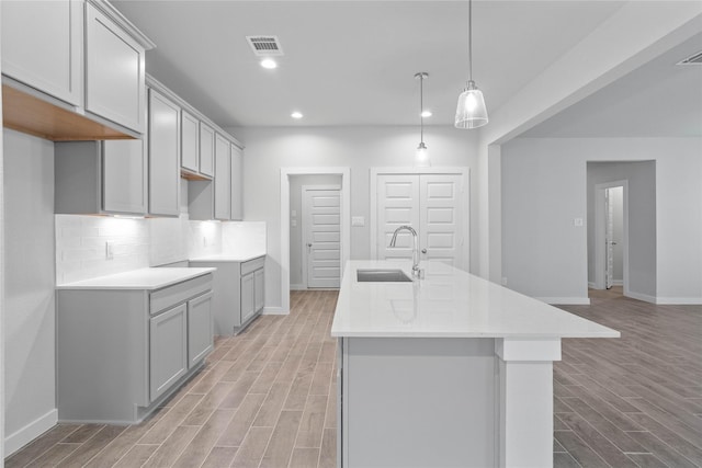 6703 Old Cypress Landing Ln, Humble, TX 77338 - kitchen with baseboards, an island with sink, light wood-style floors, visible vents, and a sink