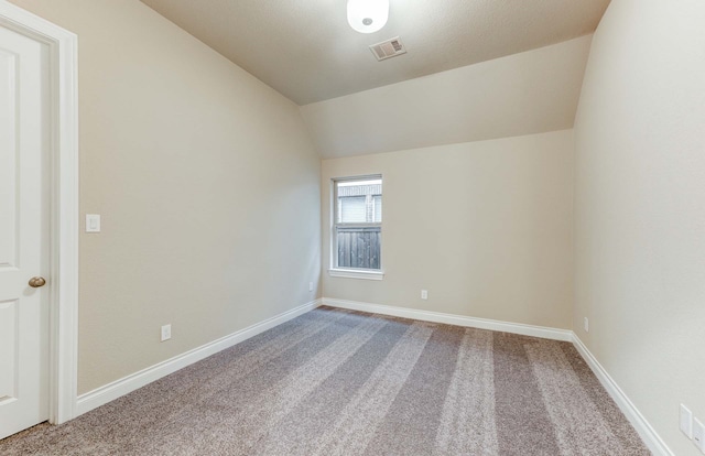 empty room featuring lofted ceiling and carpet