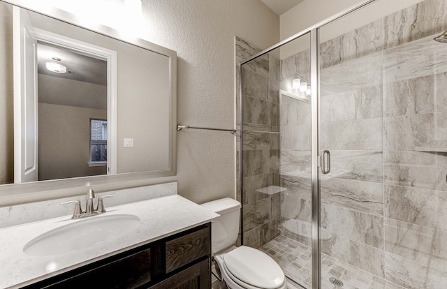 bathroom featuring vanity, toilet, and a shower with shower door