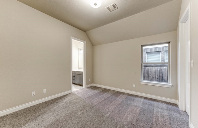 carpeted empty room with lofted ceiling and a textured ceiling