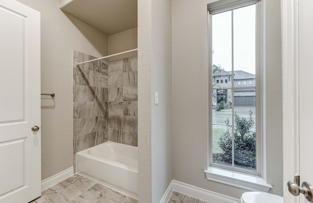 bathroom featuring tiled shower / bath, toilet, and a wealth of natural light