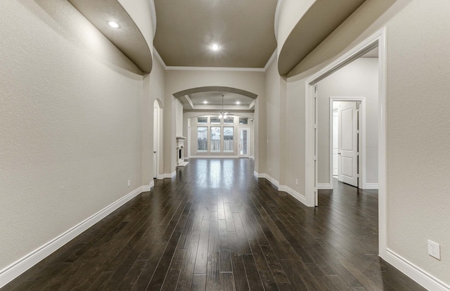 hallway with crown molding, dark wood-type flooring, and a tray ceiling