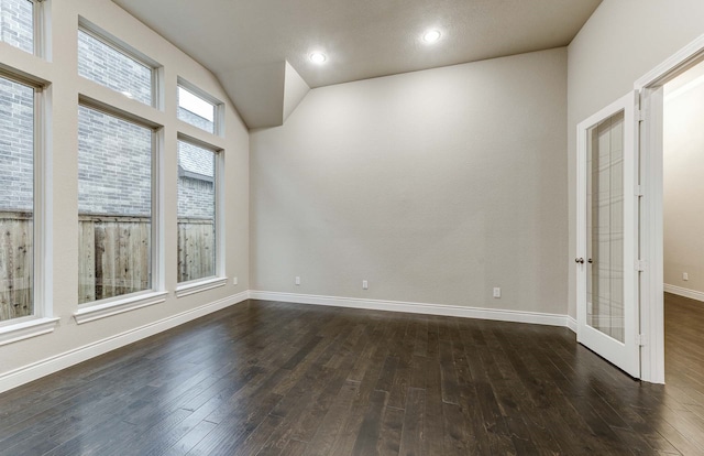 spare room featuring vaulted ceiling and dark wood-type flooring