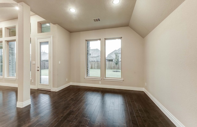 interior space with dark hardwood / wood-style flooring, vaulted ceiling, and a textured ceiling