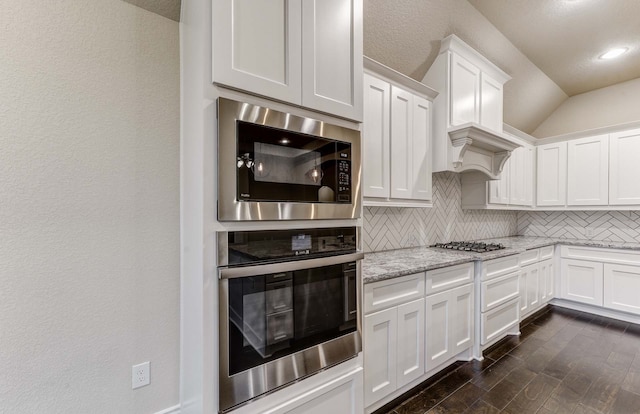 kitchen featuring white cabinetry, stainless steel appliances, light stone countertops, and decorative backsplash