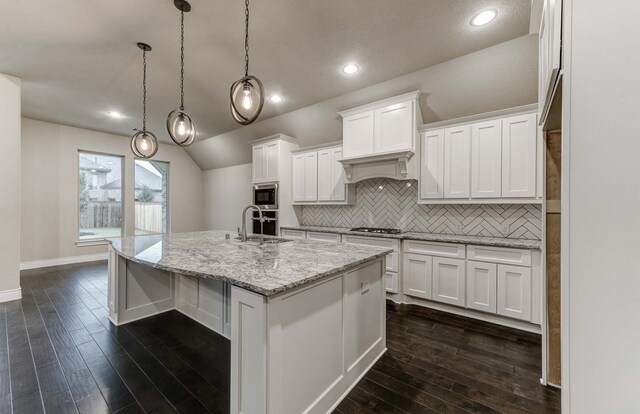 kitchen with pendant lighting, sink, a kitchen island with sink, stainless steel appliances, and white cabinets