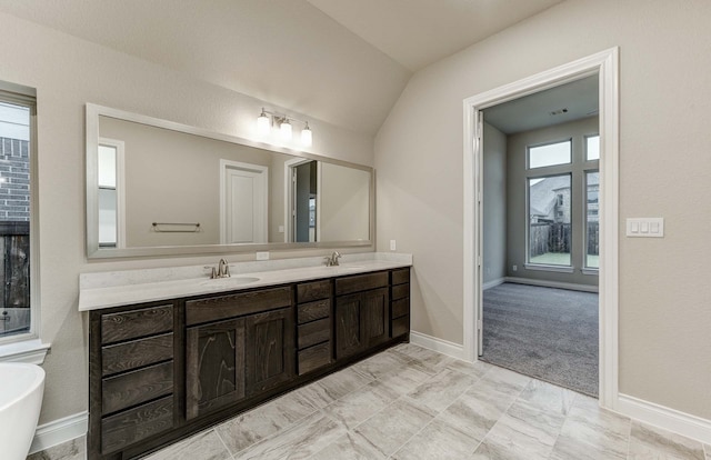 bathroom featuring vanity, vaulted ceiling, and a bathing tub