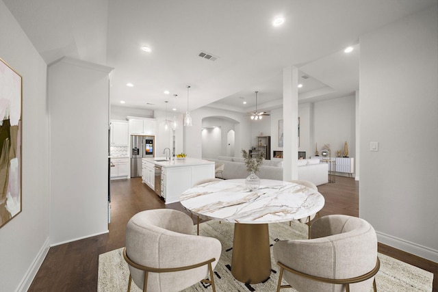 dining area featuring sink, dark hardwood / wood-style floors, and a tray ceiling