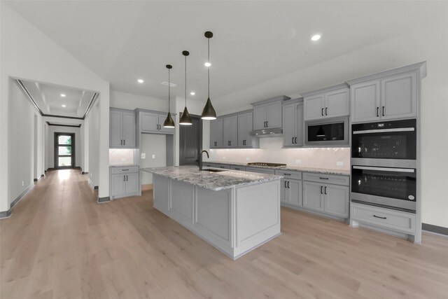 16179 Sheridan River Trl, Conroe, TX 77302 - kitchen with stainless steel appliances, light wood finished floors, gray cabinets, under cabinet range hood, and recessed lighting