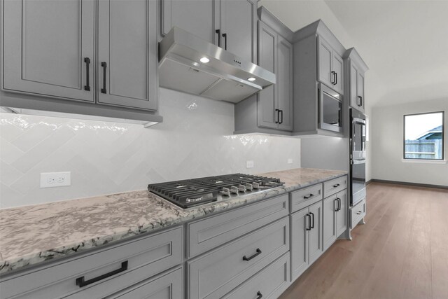 16179 Sheridan River Trl, Conroe, TX 77302 - kitchen with range hood, stainless steel appliances, decorative backsplash, gray cabinetry, and light wood-style floors