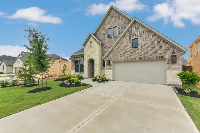 16179 Sheridan River Trl, Conroe, TX 77302 - french country style house featuring stone siding, driveway, brick siding, and an attached garage