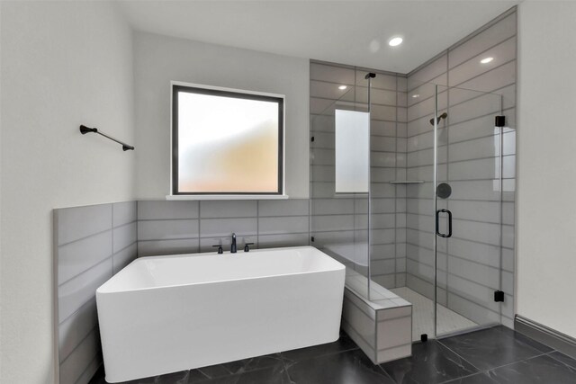 16179 Sheridan River Trl, Conroe, TX 77302 - bathroom with marble finish flooring, a shower stall, a freestanding bath, tile walls, and recessed lighting